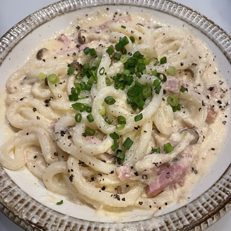 花いちのカルボナーラうどん。青ねぎと黒こしょうをかけたクリームのうどん